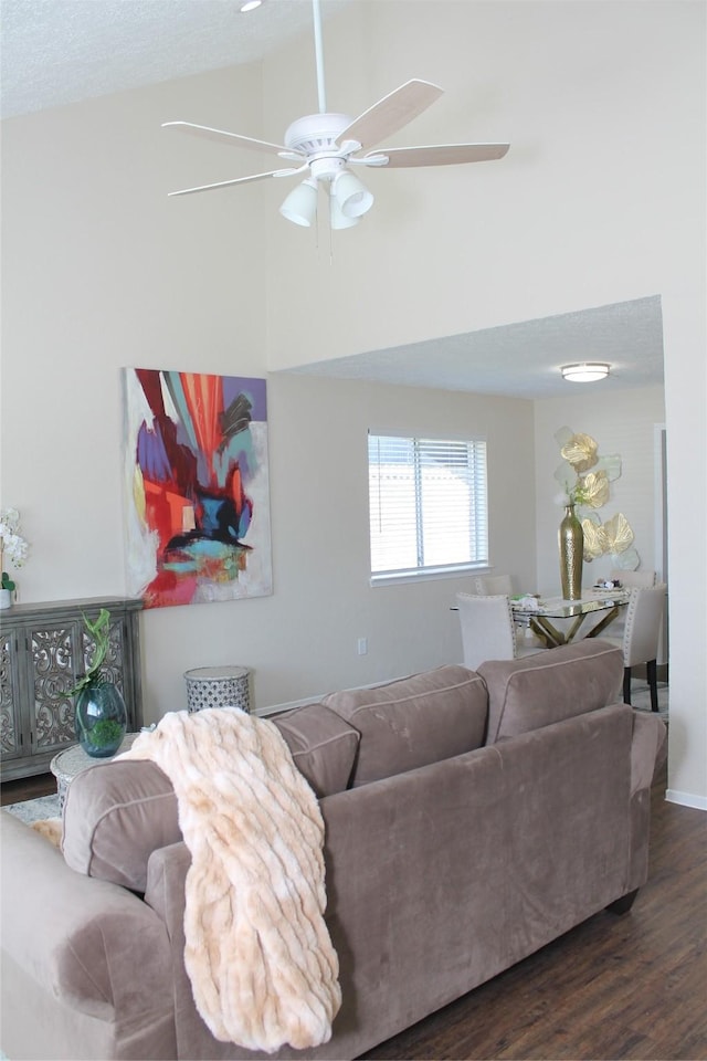 living area with wood finished floors, a ceiling fan, baseboards, and high vaulted ceiling