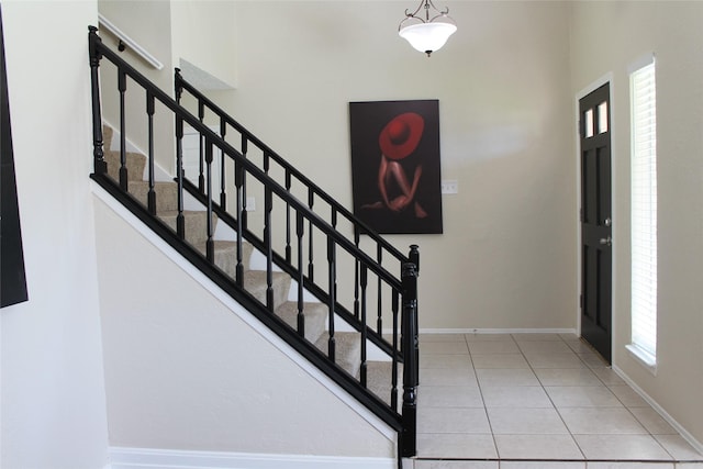 foyer with light tile patterned flooring, stairs, and baseboards