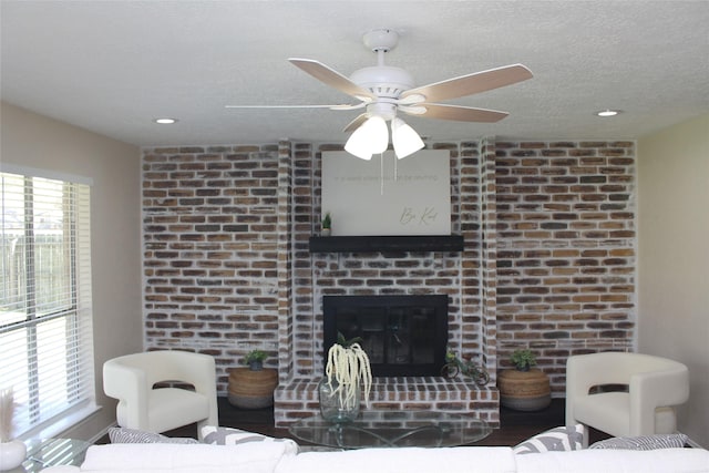 living room featuring a wealth of natural light, a textured ceiling, ceiling fan, and a fireplace