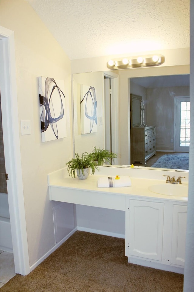 bathroom featuring vanity, lofted ceiling, carpet flooring, and a textured ceiling