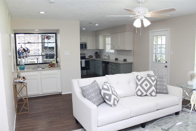 living room with plenty of natural light, a textured ceiling, dark wood-style flooring, and a ceiling fan