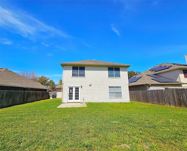 rear view of house with a yard, a fenced backyard, and french doors