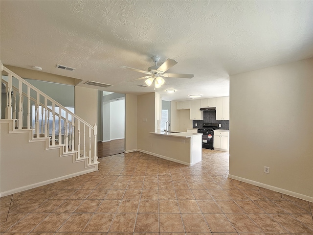 unfurnished living room with visible vents, baseboards, ceiling fan, stairs, and a sink