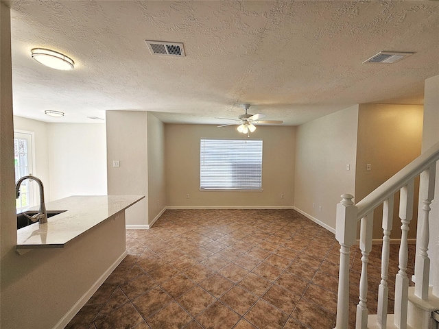 unfurnished living room featuring a sink, visible vents, and plenty of natural light