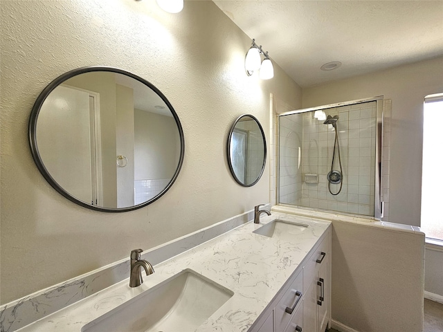 bathroom with a sink, double vanity, and a tile shower