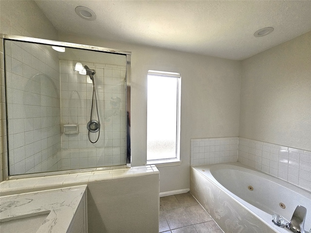 bathroom featuring tile patterned flooring, baseboards, tiled shower, a tub with jets, and a textured ceiling