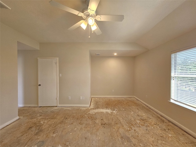 empty room with visible vents, ceiling fan, lofted ceiling, and baseboards