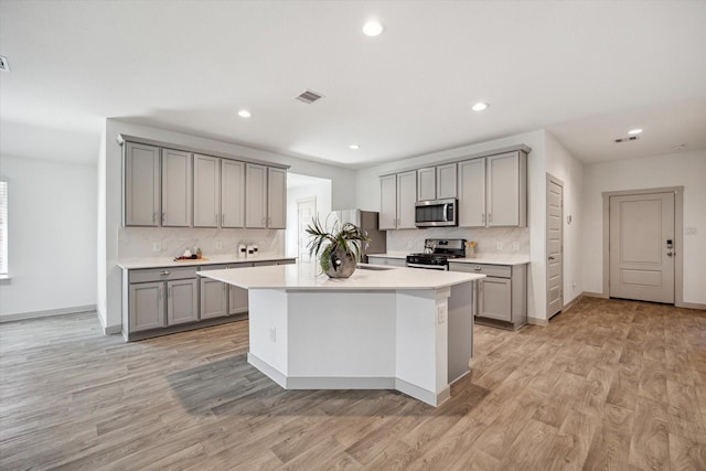 kitchen with visible vents, gray cabinets, stainless steel appliances, light wood-style floors, and light countertops