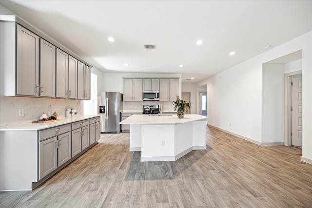 kitchen featuring visible vents, decorative backsplash, gray cabinets, appliances with stainless steel finishes, and light wood-style flooring