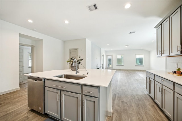 kitchen featuring visible vents, gray cabinets, a sink, stainless steel dishwasher, and light wood-style floors