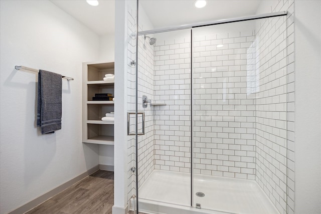 full bath with a stall shower, baseboards, and wood finished floors