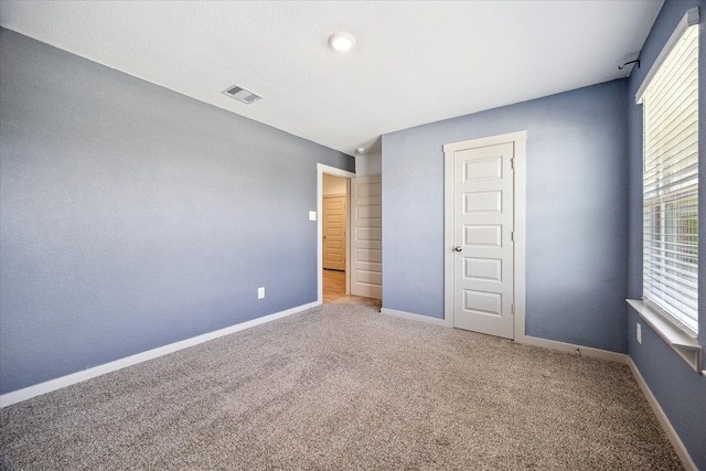 unfurnished bedroom with carpet flooring, baseboards, and visible vents