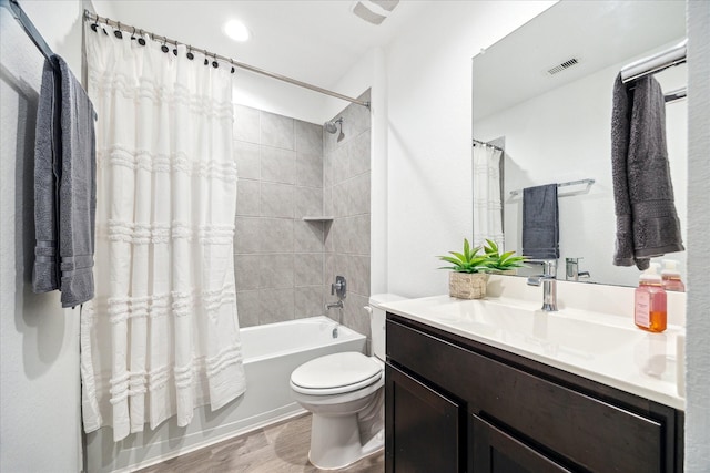 bathroom with visible vents, toilet, wood finished floors, shower / tub combo, and vanity