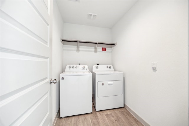 clothes washing area featuring visible vents, washing machine and dryer, light wood-style floors, baseboards, and laundry area