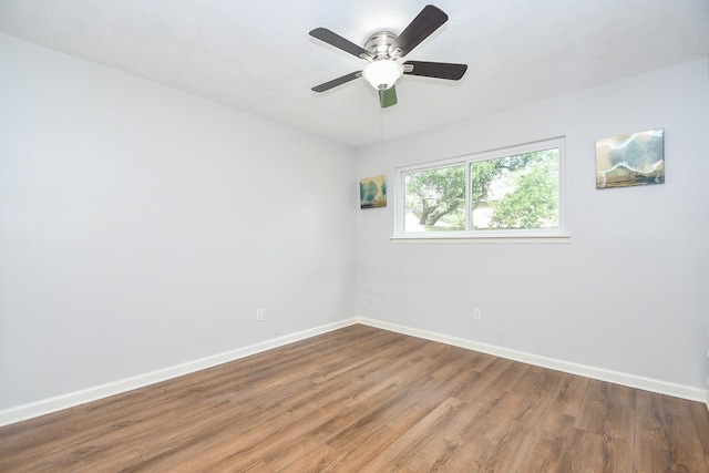 spare room featuring a ceiling fan, baseboards, and wood finished floors