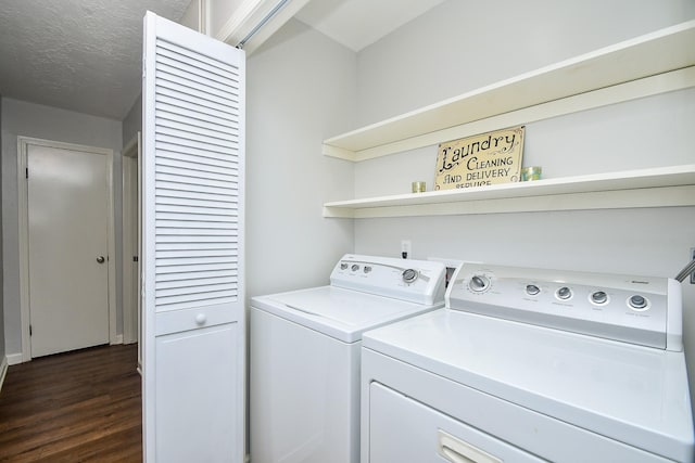 washroom featuring a textured ceiling, laundry area, dark wood-type flooring, and washer and clothes dryer