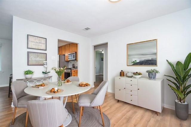 dining room featuring visible vents, light wood-style flooring, and baseboards