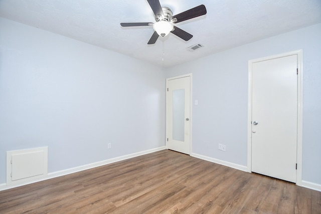 unfurnished room with baseboards, wood finished floors, visible vents, and ceiling fan