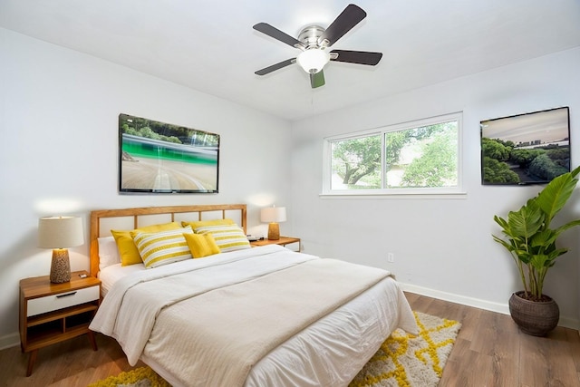 bedroom featuring ceiling fan, baseboards, and wood finished floors