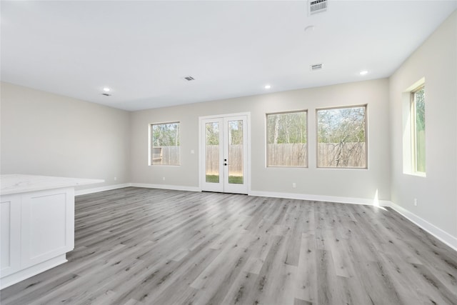 unfurnished living room featuring visible vents, french doors, and light wood-style floors