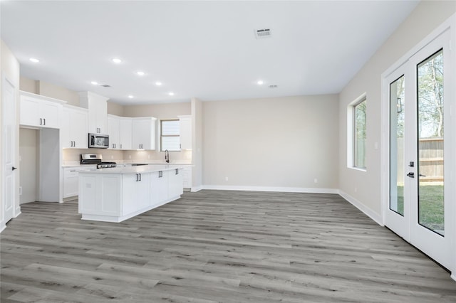 kitchen with light wood finished floors, open floor plan, light countertops, appliances with stainless steel finishes, and white cabinets