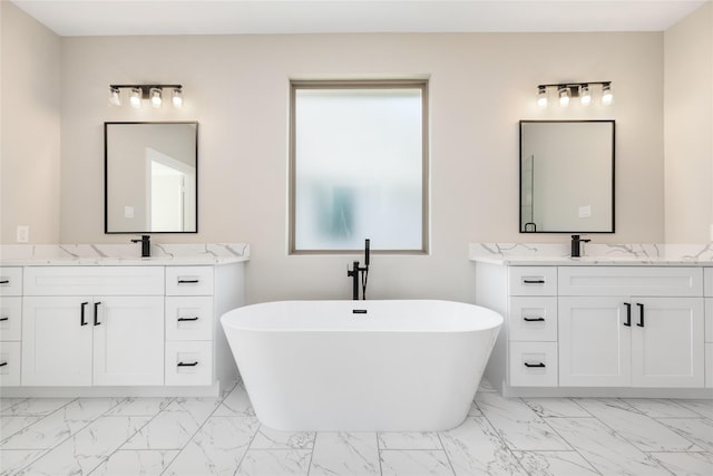 bathroom with a sink, marble finish floor, a freestanding bath, and two vanities