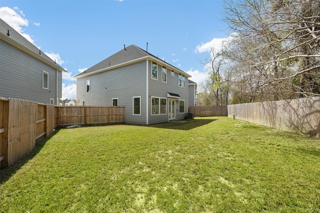 back of property with a fenced backyard, central AC unit, and a yard