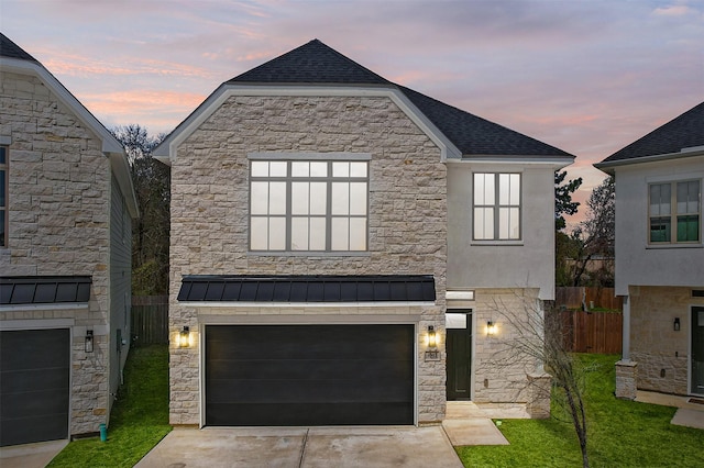 view of front of house with fence, roof with shingles, an attached garage, concrete driveway, and stone siding