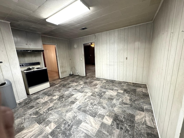 kitchen with electric stove, visible vents, and wood walls