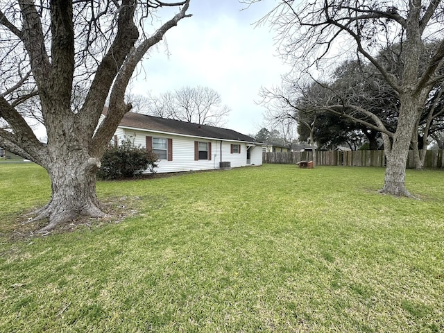 view of yard with central AC and fence