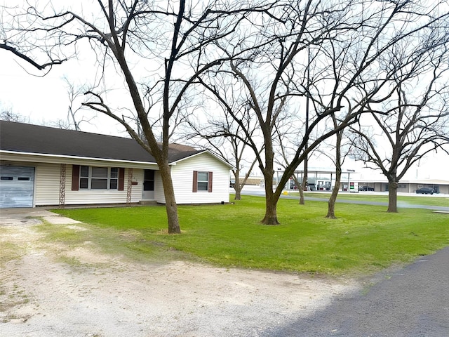 view of front facade featuring a front lawn, a garage, and dirt driveway