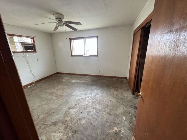 unfurnished bedroom with a closet, multiple windows, baseboards, and cooling unit