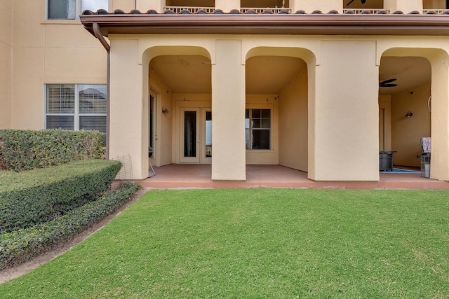 back of house featuring a lawn, french doors, a patio, and stucco siding