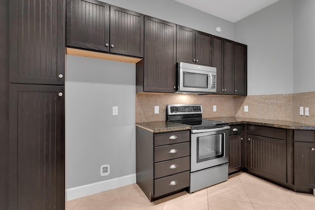 kitchen with dark stone countertops, decorative backsplash, appliances with stainless steel finishes, and light tile patterned floors