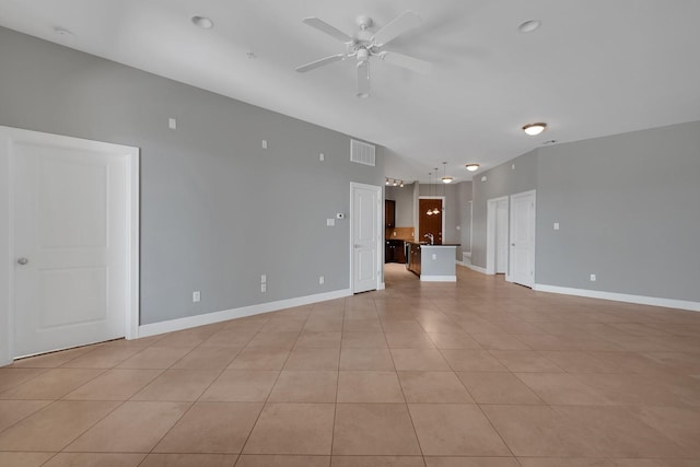 unfurnished living room with visible vents, a ceiling fan, a sink, light tile patterned floors, and baseboards