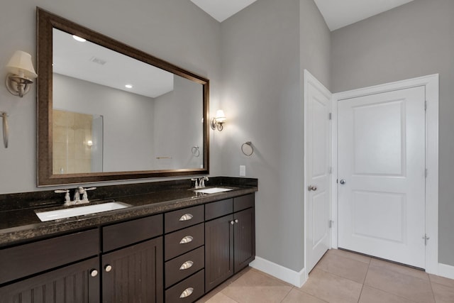 bathroom featuring tile patterned floors, double vanity, baseboards, and a sink