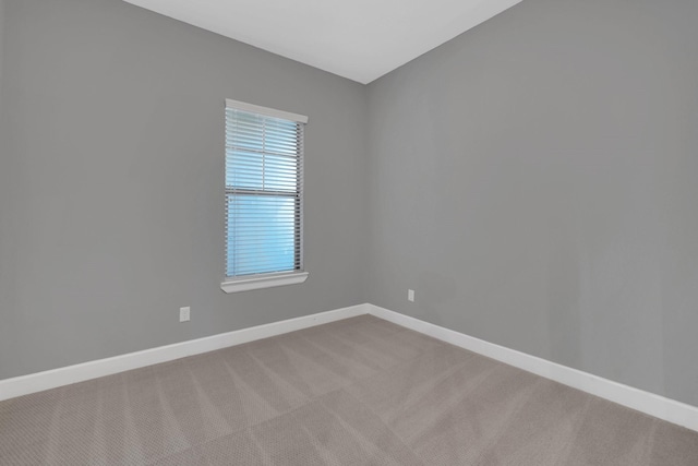 spare room with baseboards and light carpet