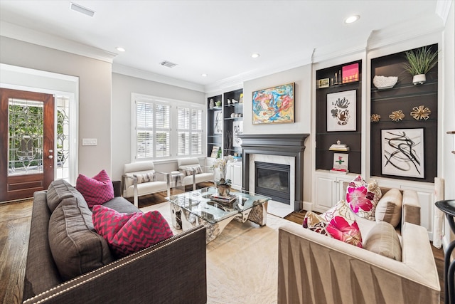 living area featuring a healthy amount of sunlight, a fireplace, built in shelves, and ornamental molding