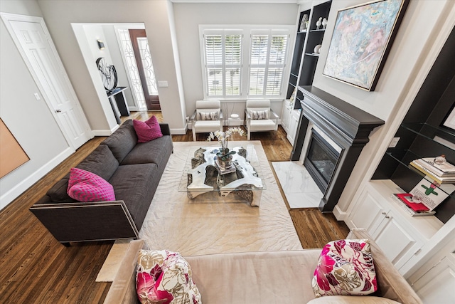 living room with a fireplace with flush hearth, baseboards, and wood finished floors