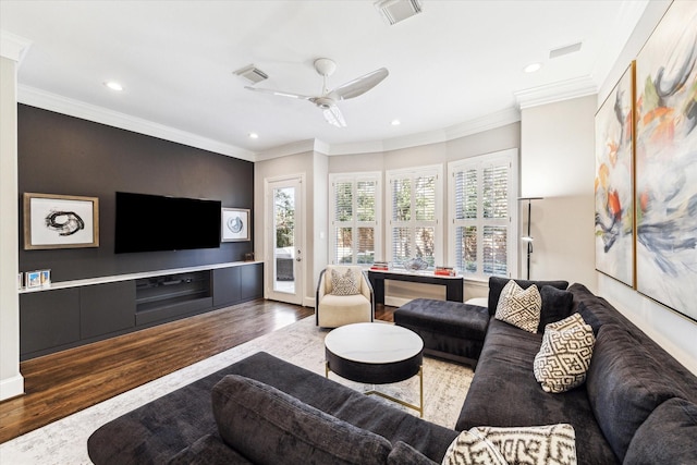 living room featuring visible vents, a ceiling fan, wood finished floors, and crown molding