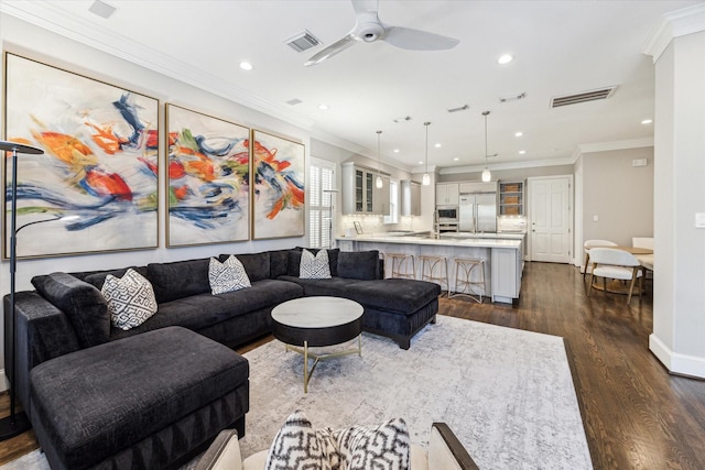 living area featuring visible vents, ceiling fan, and crown molding