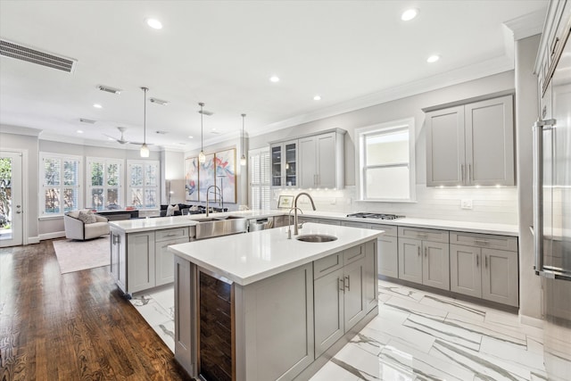 kitchen with a sink, visible vents, a kitchen island with sink, and gray cabinets