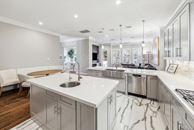 kitchen featuring visible vents, dishwasher, an island with sink, gray cabinets, and a sink