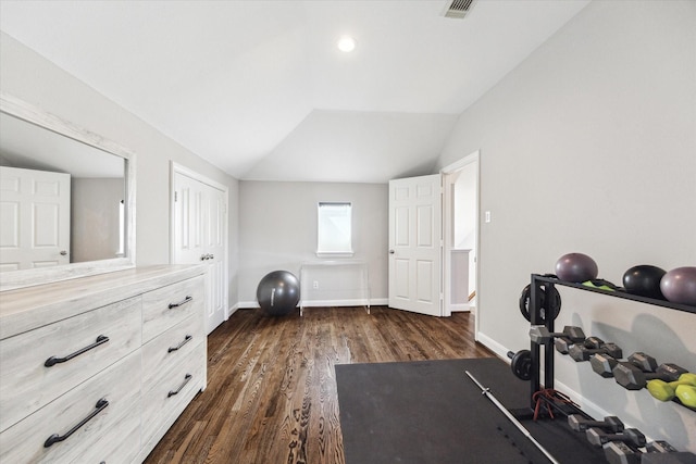 exercise room featuring visible vents, baseboards, dark wood finished floors, and vaulted ceiling