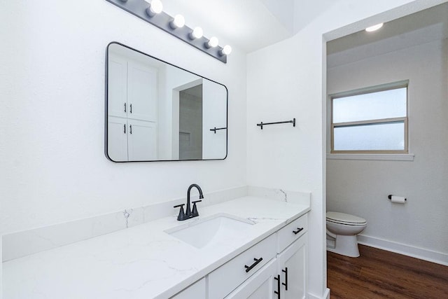 bathroom with vanity, toilet, wood finished floors, and baseboards