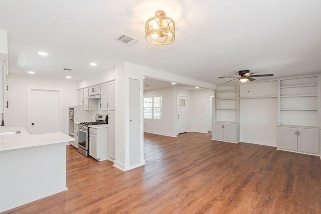 kitchen with light wood finished floors, gas range, light countertops, recessed lighting, and a ceiling fan