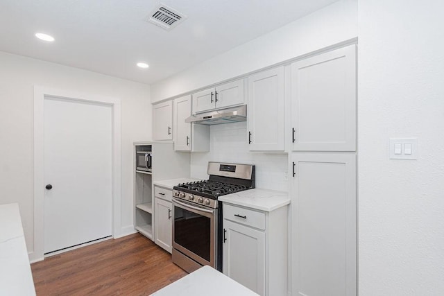 kitchen featuring visible vents, dark wood-style flooring, stainless steel appliances, decorative backsplash, and under cabinet range hood