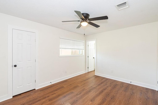 unfurnished room featuring a ceiling fan, wood finished floors, visible vents, and baseboards