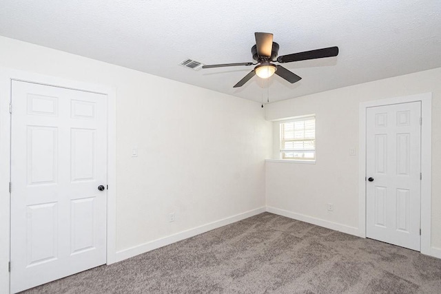 carpeted spare room with visible vents, baseboards, a textured ceiling, and a ceiling fan