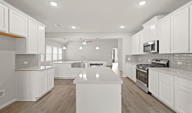 kitchen with visible vents, a center island, ceiling fan, appliances with stainless steel finishes, and a sink